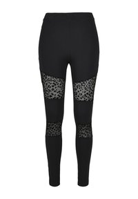 Čierne legíny s priehľadnými leopardími vzormi na stehnách. Hladká látka, priliehavý strih a elastický pás.