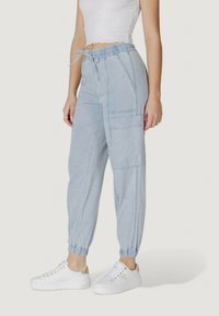Pantaloni cargo de culoare albastru deschis, cu talie elastică, detalii cu șnur și manșete tapered. Prezintă buzunare laterale și linii de cusătură subtile.