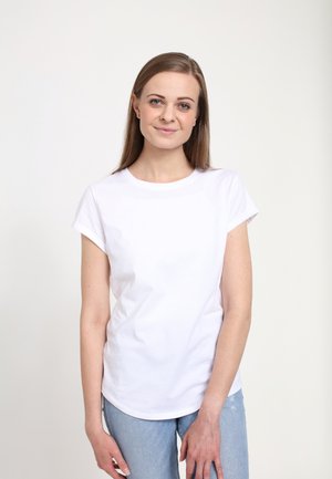 Bílá tričko s krátkým rukávem a kulatým výstřihem, vyrobené z bavlny, spárované se světle modrými roztrhanými džíny. Minimalistický design.