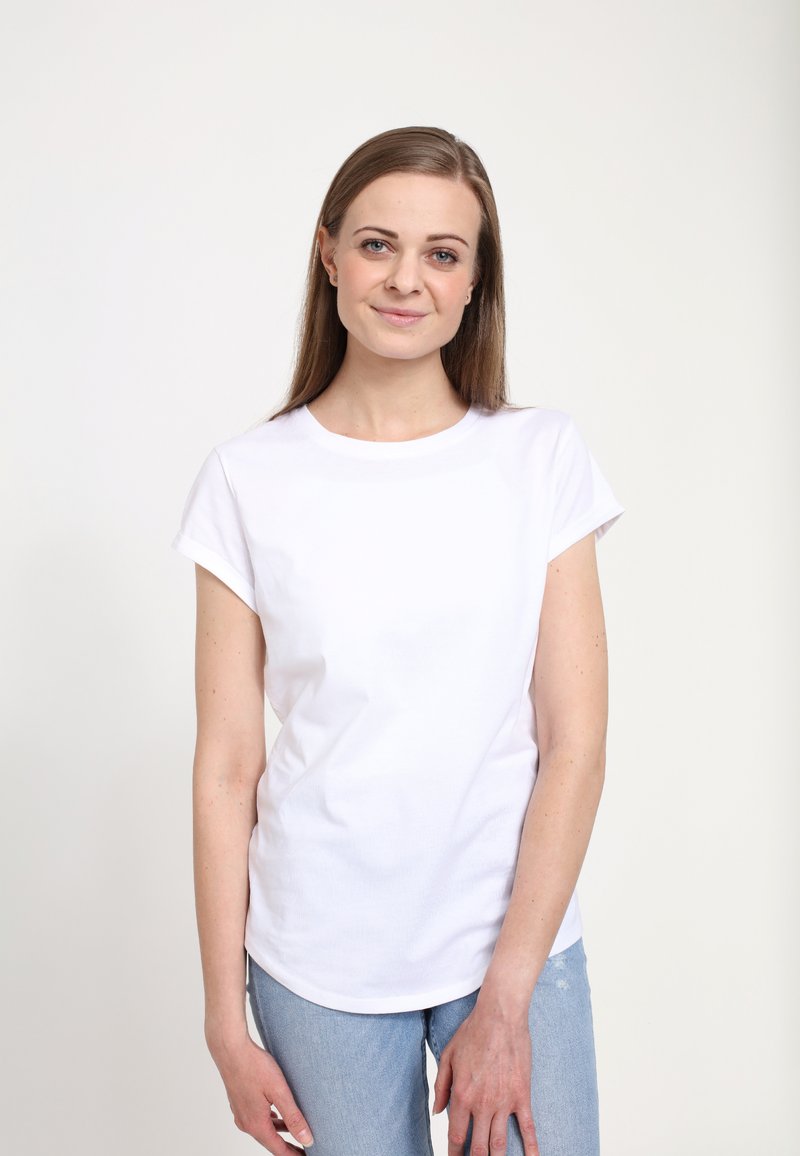 Hvid kortærmet t-shirt med rund halsudskæring, lavet af bomuldsstof, parret med lyseblå slidte jeans. Minimalistisk design.