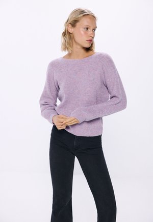 Lilac knit sweater with a wide scoop neck and textured sleeves, paired with black jeans. Soft fabric and relaxed fit for comfort.