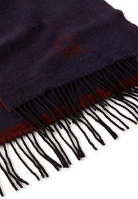 Tmavě modrý a burgundský vlněný šátek s třásněmi, který má jemný tónový vzor a dekorativní emblém v tmavším odstínu.