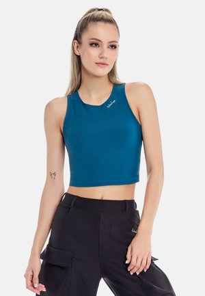 Tirkizni crop top u prilagođenom dizajnu s okruglim izrezom i bez rukava. Ima mali logo akcent i glatku teksturu. Uparen s crnim cargo hlačama.