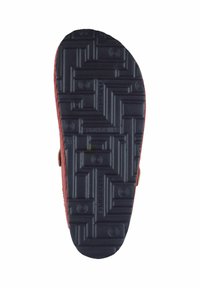 Rote Wildledersohle mit einem strukturierten schwarzen Gummiuntergrund. Das Muster zeigt ein geometrisches Design mit runden Eindrücken und Markenlogos.