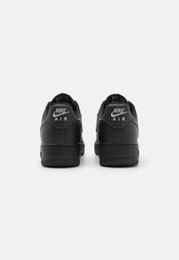 Μαύρα αθλητικά παπούτσια Nike Air από δέρμα, με στρογγυλή σχεδίαση, λογότυπο στη φτέρνα και υφασμένη ελαστική σόλα για πρόσφυση και ανθεκτικότητα.