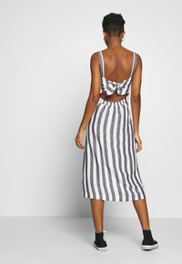 Pruhované šaty s přiléhavým korzetem, tenkými ramínky a mašlí na zadní straně. Mají lehkou, dlouhou sukni v černé a bílé barvě.