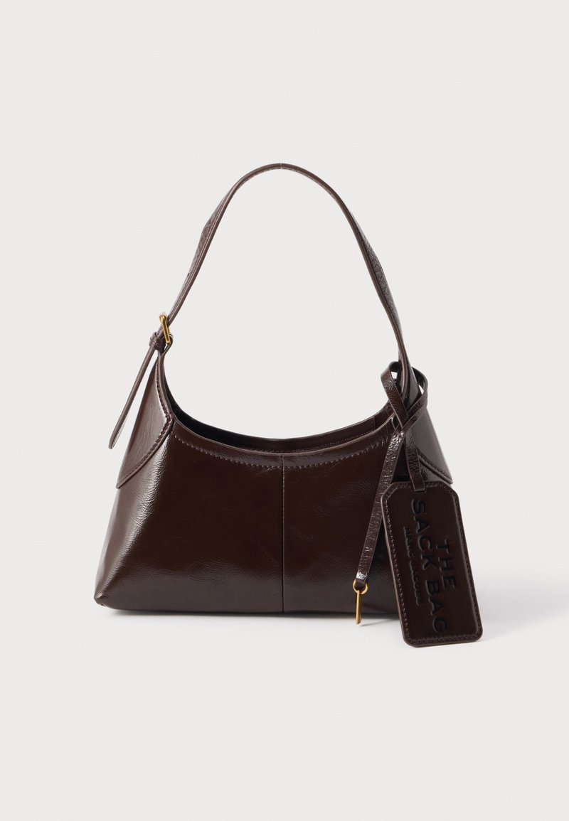 Sac à bandoulière en cuir marron foncé avec une sangle courbée et une étiquette rectangulaire embossée de "The Sack Bag" sur un fond uni.