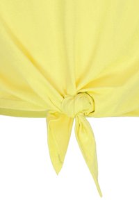 Top in tessuto giallo annodato con una superficie liscia. Il dettaglio del nodo è evidente al centro, creando una drappeggio asimmetrico.
