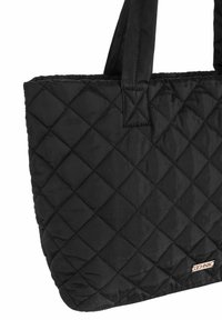 Czarna torba tote z pikowanej tkaniny, z podwójnymi uchwytami i małą prostokątną metalową łatą marki w dolnym rogu.