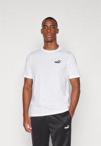 Witte katoenen t-shirt met korte mouwen en een ronde hals, voorzien van een klein zwart Puma-logo op de borst. Glad textuur, klassieke pasvorm.