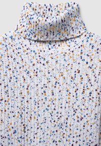 Knitted turtleneck sweater in white with multicolored speckles of purple, blue, yellow, and green; textured pattern throughout.