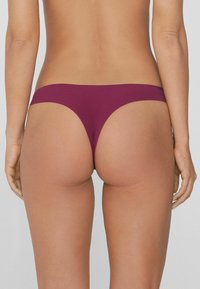 Bikiniunterteil in einem tiefen Burgunderrot, mit einem minimalen Schnitt, einer glatten Textur und einem tief sitzenden Bund.