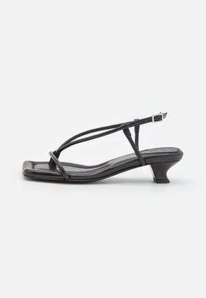 Sandale negre din piele cu curele subțiri, toc mic pătrat și vârf pătrat. Prezintă o închidere cu cataramă și o textură netedă.