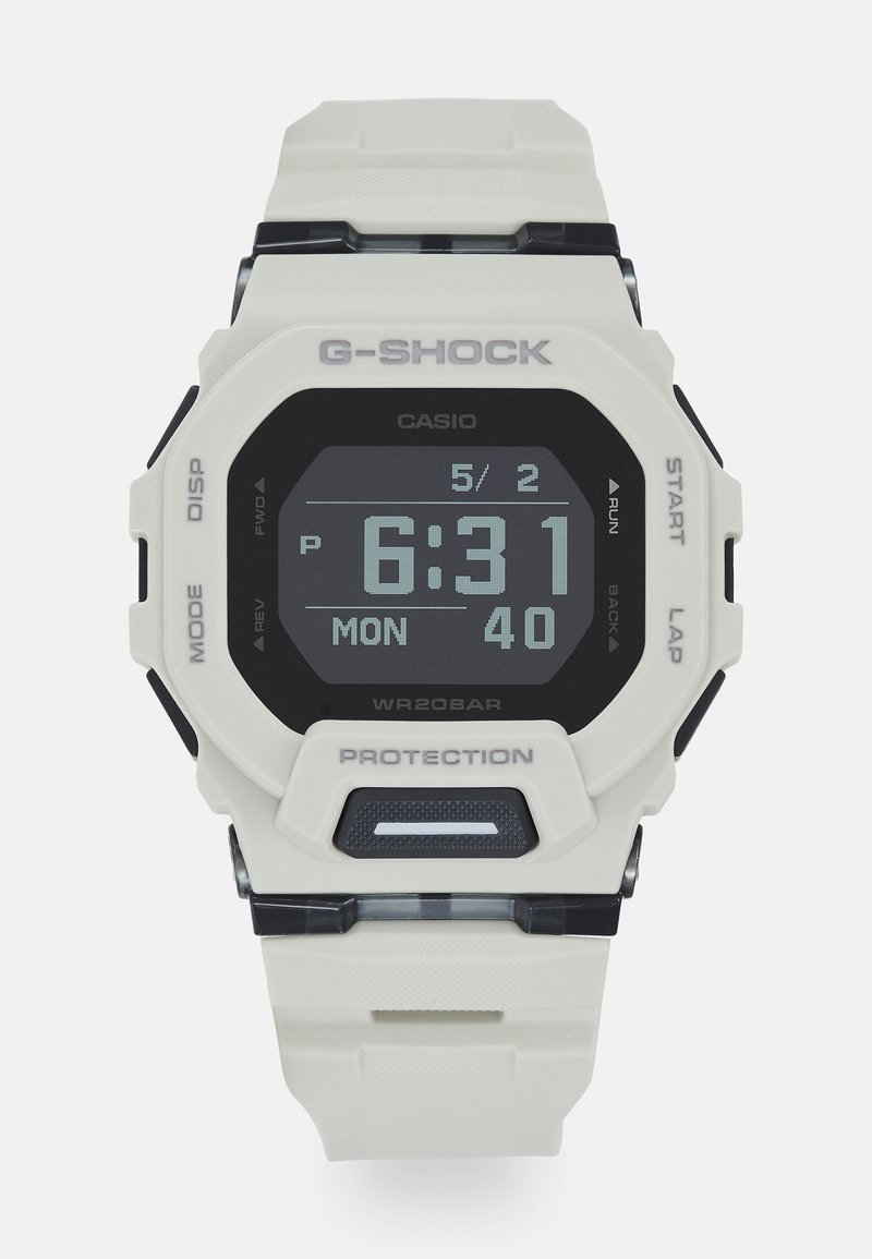 G-Shock digitaalkell, millel on valge plastikraam ja -rihm, must digitaalne kuvand ja hallid aktsendid. Omab nuppe režiimi ja taimeri jaoks.