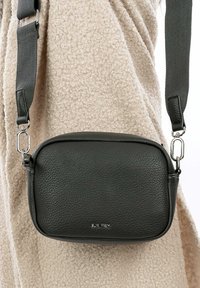 Borsa a tracolla in pelle grigia scura con una texture liscia, forma rettangolare, tracolla in tessuto regolabile e dettagli in metallo argentato.