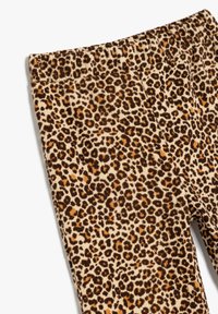 Kapezuste zhangau zikhudhowu zexhonywe zokhuni ezinephewu, brown, kunye nebhaki ye-leopard ithungwe kwi-m тканом ebanzi, iboniswe ukusuka ibhantshi ukuya phezulu kwe-chino.