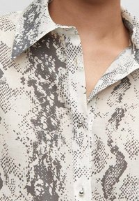 Leichtes, gemustertes Hemd in Beige- und Grautönen mit klassischem Kragen, durchgehender Knopfleiste und dezent strukturiertem Stoff.