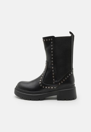 Sort mid-kalv læderstøvle med chunky sål, elastisk ribbet sidepanel og dekorative runde sølvnitter langs sømmene.