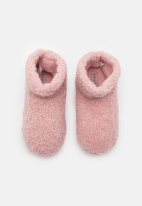 Rosa, fluffiga tofflor gjorda av mjukt, strukturerat tyg. Halvhögt utförande med rullad mudd och plyschinredning. Rundad form.