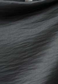 Tejido negro con una textura suave y un sutil patrón de ondas. El material parece ligero, con un suave brillo y sin adornos visibles.