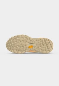 Semelle de chaussure beige avec des crampons profonds et un logo Vibram jaune au centre, conçue pour la traction sur les surfaces rugueuses.