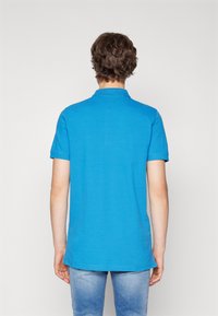 Polo shirt blu attillato con maniche corte, realizzato in un tessuto liscio, con colletto classico e orlo dritto.