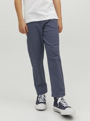 Mörkblå bomullbyxor med rak ben-design, i kombination med vita sneakers som har mörkblå detaljer och en vit gummisula.