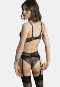 Ensemble de soutien-gorge en dentelle noire et de porte-jarretelles avec des détails transparents. Comprend des bretelles réglables, une fermeture à crochet et des motifs floraux sur le tissu.
