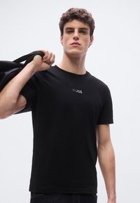 Μαύρο βαμβακερό t-shirt με στρογγυλή λαιμόκοψη και κοντά μανίκια, με διακριτικό λογότυπο "BOSS" σε αντίθετη κεντητική στο στήθος.