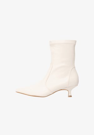 Bottine blanche en matière lisse avec un bout pointu et un petit talon kitten bas. Design simple avec des détails de coutures discrètes.