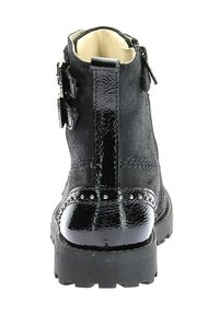 Bottines noires avec un dessus en suède texturé et des accents en cuir verni brillant, dotées de deux boucles sur les côtés et d'une semelle en caoutchouc épaisse.