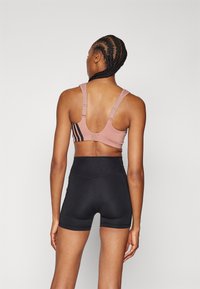 Sport-bh i støvete rosa med svarte striper, med justerbare stropper og racerback-design. Høyt midjesvart shorts.