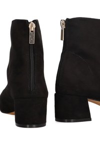 Botines de ante negro con tacón corto y grueso y cremalleras laterales. El material tiene una textura suave y las cremalleras cuentan con accesorios de hardware plateados.