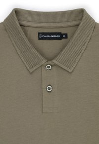 Khaki polo shirt z prążkowanym kołnierzykiem, trzema srebrnymi guzikami i etykietą z materiału. Teksturowany bawełniany materiał. Rozmiar M.