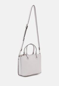 Mała jasnoszara skórzana torebka na podwójnych uchwytach z długim regulowanym paskiem na ramię na jednolitym tle.