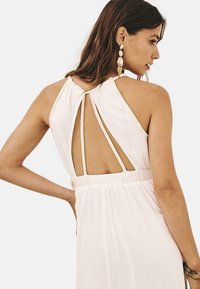 Vestido blanco sin mangas con un diseño de abertura en la espalda, con tirantes entrelazados y una cintura fruncida. Textura suave, estilo minimalista.
