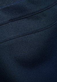 Ciemnoniebieska elastyczna tkanina o gładkiej teksturze, z lekko podwyższonym pasem i starannymi detalami ściegów przy szwach.