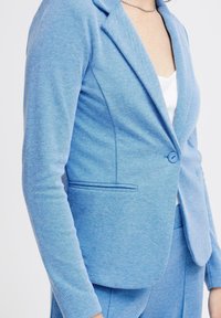 Blazer azzurro chiaro realizzato in tessuto testurizzato, con colletto a rever, chiusura a un bottone e tasche laterali, dal taglio su misura.