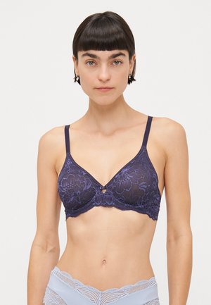 Navy lace bra with floral pattern, underwire support, adjustable straps, and a small central bow detail. The fabric features a textured finish.