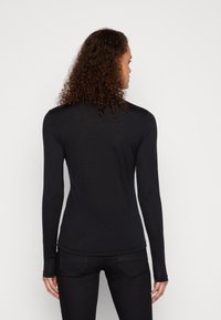Long-sleeve black top made of soft fabric, featuring a fitted design, smooth texture, and rounded neckline. Back view displayed.