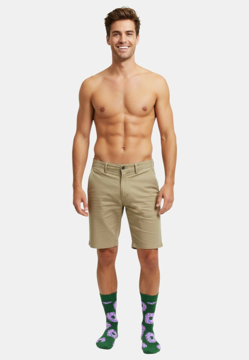 Khaki-Shorts mit Knopfverschluss, kombiniert mit grünen Socken im Donut-Muster. Die Shorts haben einen geraden Schnitt und eine strukturierte Stoffoberfläche.