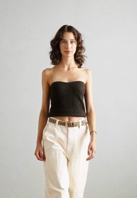 Top sans bretelles côtelé marron foncé, pantalon taille haute de couleur claire et ceinture en imprimé léopard avec une boucle circulaire. Texture lisse, design ajusté.