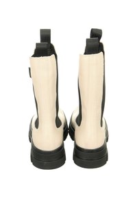 Beige Leder-Ankle Boots mit schwarzen elastischen Seiteneinsätzen und Gummisohlen; verfügen über Zuglaschen hinten und eine strukturierte schwarze Sohle.