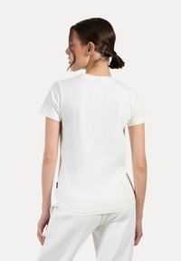 Hvid bomulds t-shirt med korte ærmer, rund halsudskæring og en afslappet pasform. Materialet har en glat tekstur; mærke synligt ved sidesømmen.