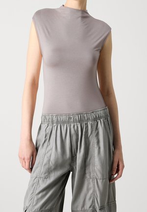 Mouwloze, lichtgrijze top van zachte stof met een hoge halslijn, gecombineerd met losse, lichtgrijze broek met elastische tailleband.