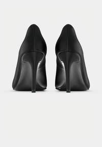 Μαύρα παπούτσια στιλέτο με ψηλό τακούνι, λεία δερμάτινη υφή, μυτερή μύτη και λεπτά τακούνια στιλέτο. Η πλευρική όψη τονίζει το σχήμα και την τεχνική.