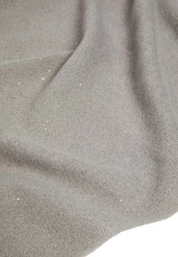 Tessuto grigio con una morbida texture, caratterizzato da lievi riflessi luccicanti che creano un effetto scintillante sulla superficie. Pieghe lisce e fluide.