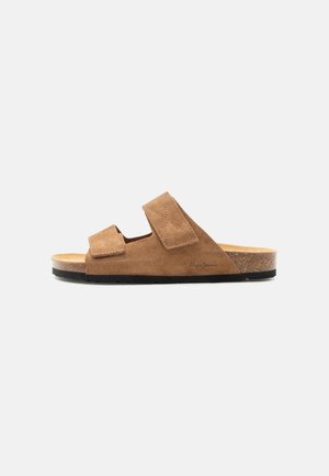 Brown suede open-toe slide sandal with two adjustable straps and cork footbed on black sole, side view