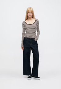 Pikad varrukadega triibuline topp kaelusega, mis on kombineeritud laia säärega tumedate teksade ja mustade tossudega. Lihtne disain, mugav istuvus.