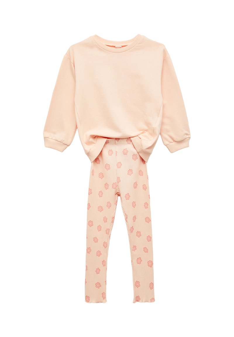 Miękki brzoskwiniowy sweter z długim rękawem w zestawieniu z prążkowanymi legginsami w różowy kwiatowy wzór, zaprezentowany na białym tle.